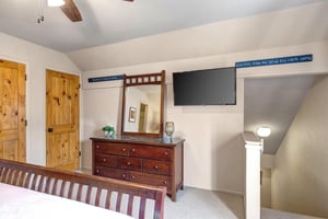 The third bedroom with a king size bed, dresser with mirror and flat screen TV.