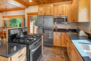 The well equipped kitchen has stainless appliances, black granite counters, and wood cabinets.