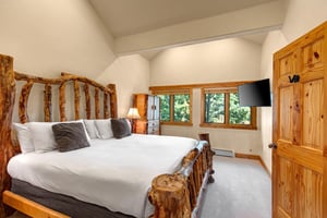 The main suite with a kingsize bed and flat screen TV mounted on the wall.