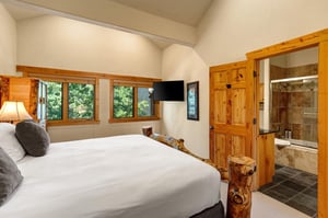 The main suite with a kingsize bed and flat screen TV mounted on the wall.