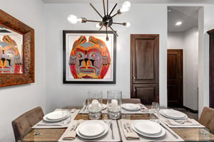 The dining area with modern lighting, colorful art and a well set table for 6 guests.