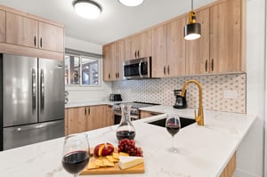 The remodeled kitchen has white oak cabinets, white counter and white and gold backsplash.