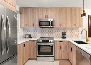The beautiful kitchen has stainless steel appliances, warm wood cabinets, and white accents.