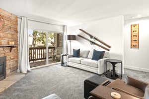 The living room has a new comfortable couch, wooden skis and modern lighting.