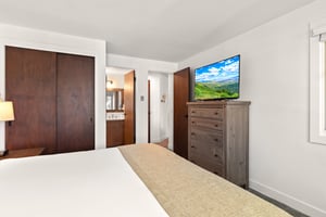 The main suite with a king size bed, tall dresser, and flat screen TV.