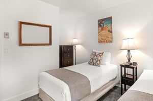 The second bedroom has two twin beds and tall dresser.
