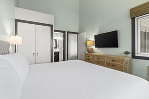 The main suite has a king size bed, dresser, and flat screen TV.