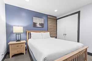 The second bedroom has a queen size bed and light wood furnishings.