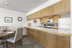 The dining area with seating for 5 guests and kitchen.