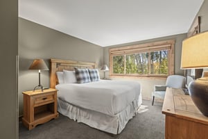 The main suite with a king size bed and views of the aspen grove out of a large window.