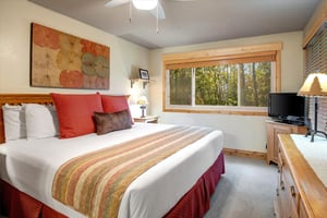 The en suite bedroom with a king size bed and large window with forest views.