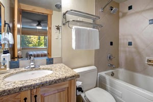 The en suite bathroom with a single sink vanity and a bathtub and shower combination.