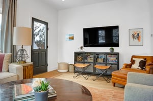 Wall mounted TV in the apres room above a black cabinet with glass doors, and a leather club chair and well designed décor.