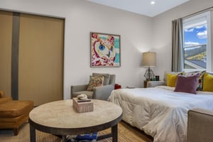 Sleeper sofa made into a queen sized bed with crisp white linens and colorful decor and barn door closure in the apres room.
