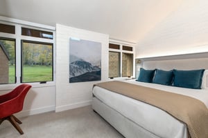 A main suite with a king size bed and windows overlooking the golf course.