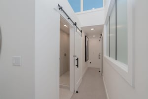 The hallway with white walls, black hardware, and natural lighting.