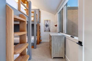 The third bedroom with two twin bunk beds, dresser, and large window.