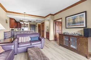Relax in your spacious living area featuring comfortable leather seating, warm wood accents, and an open layout connecting to your fully equipped kitchen.