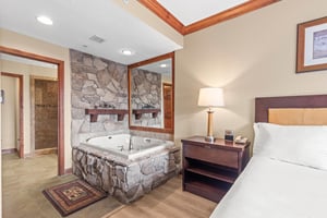Unwind in your spacious suite featuring a luxurious stonesurround soaking tub, comfortable king bed, and elegant wood finishes throughout.