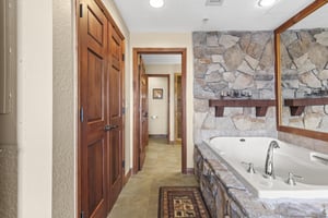 Unwind in your spalike bathroom featuring a luxurious stonewrapped soaking tub, rich wood cabinetry, and elegant finishes that create the perfect retreat for relaxation.