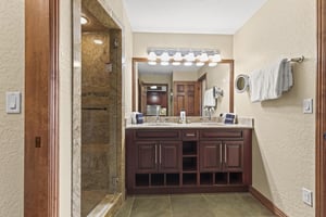 Step into your beautifully appointed bathroom with elegant granite countertops, rich wood cabinetry, and a luxurious stonetiled shower.