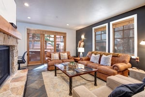 Sink into plush leather seating by your crackling stone fireplace, where large windows frame mountain views and cozy evenings await your arrival.