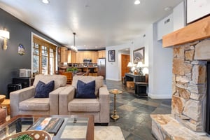 Relax in your spacious openconcept living area featuring a cozy stone fireplace, comfortable seating, and fully equipped kitchen  perfect for unwinding after a day of adventure.