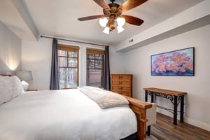 Rest peacefully in your comfortable bedroom featuring rustic wood furnishings, exposed ceiling beams, and a ceiling fan.