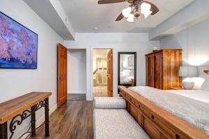 Relax in your spacious bedroom featuring beautiful wood furnishings, a comfortable seating area, and modern amenities.