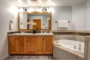 Relax in your spacious bathroom featuring a luxurious soaking tub, elegant vanity with ample storage, and thoughtful amenities.