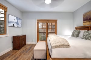Unwind in your serene bedroom featuring a comfortable bed with plush linens, modern TV for entertainment, and warm wood accents that create a peaceful retreat.