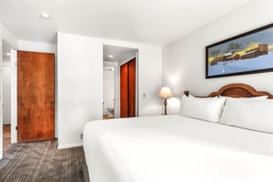Unwind in your comfortable bedroom featuring crisp white linens, warm wood accents, and thoughtful lighting that creates the perfect atmosphere for rest.