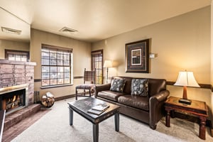 The living room with a leather sofa and a chair in the corner.