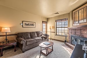 A cozy living room with one sofa, TV, gas burning fireplace, and dining table for two guests.