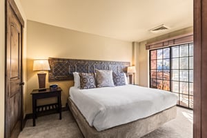 The main suite bedroom with a king size bed and large sliding glass door leading to a private patio.