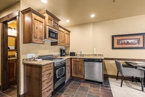 Your fully equipped kitchen awaits with warm wood cabinetry, granite counters, and stainless appliances.