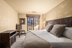 Sink into luxury in your serene bedroom, where an ornate carved headboard and plush linens create the perfect retreat.