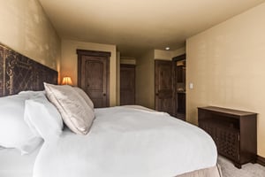 Sink into luxury in your serene bedroom, where an ornate carved headboard and plush linens create the perfect retreat.