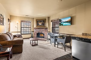A cozy living room with one sofa, TV, gas burning fireplace, and dining table for two guests.