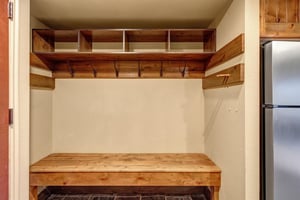 Your private mudroom awaits with custom wooden storage cubbies and hooks to keep your gear organized.