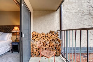 Step onto your private balcony where crisp mountain air awaits. Cozy up in the woven chair with morning coffee while admiring the rustic firewood display and city views beyond.