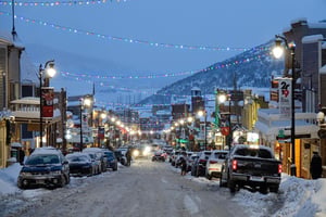 Main Street with snow on the ground and holiday lights strung across the street.