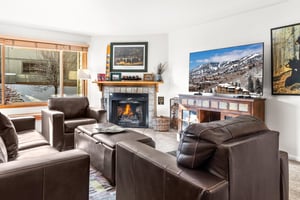Relax in your cozy living room with leather seating, warm fireplace, and large TV.