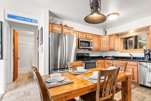 Your fully equipped kitchen features warm wood cabinetry, stainless steel appliances, and a dining table.