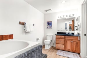 Unwind in your spacious bathroom featuring a soaking tub, dual vanity with granite countertops, and warm wood finishes.