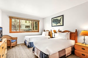 Unwind in your comfortable twin bedroom with crisp white linens, warm wood furnishings, and a cozy reading chair.