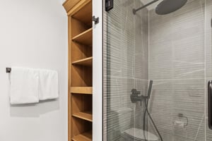 Step into your modern ensuite featuring a sleek glass shower with contemporary fixtures and convenient builtin storage for your essentials.