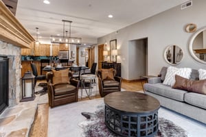 Relax in your elegantly appointed living space featuring leather armchairs, a cozy fireplace, and seamless flow to your fully equipped kitchen