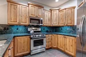 Your fully equipped kitchen features beautiful wood cabinets, granite countertops, stainless steel appliances, and a stunning turquoise glass backsplash  everything you need to prepare meals during y