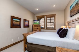 Unwind in this cozy bedroom featuring rustic wood furnishings, crisp white linens, and your own flatscreen TV for relaxing evenings.